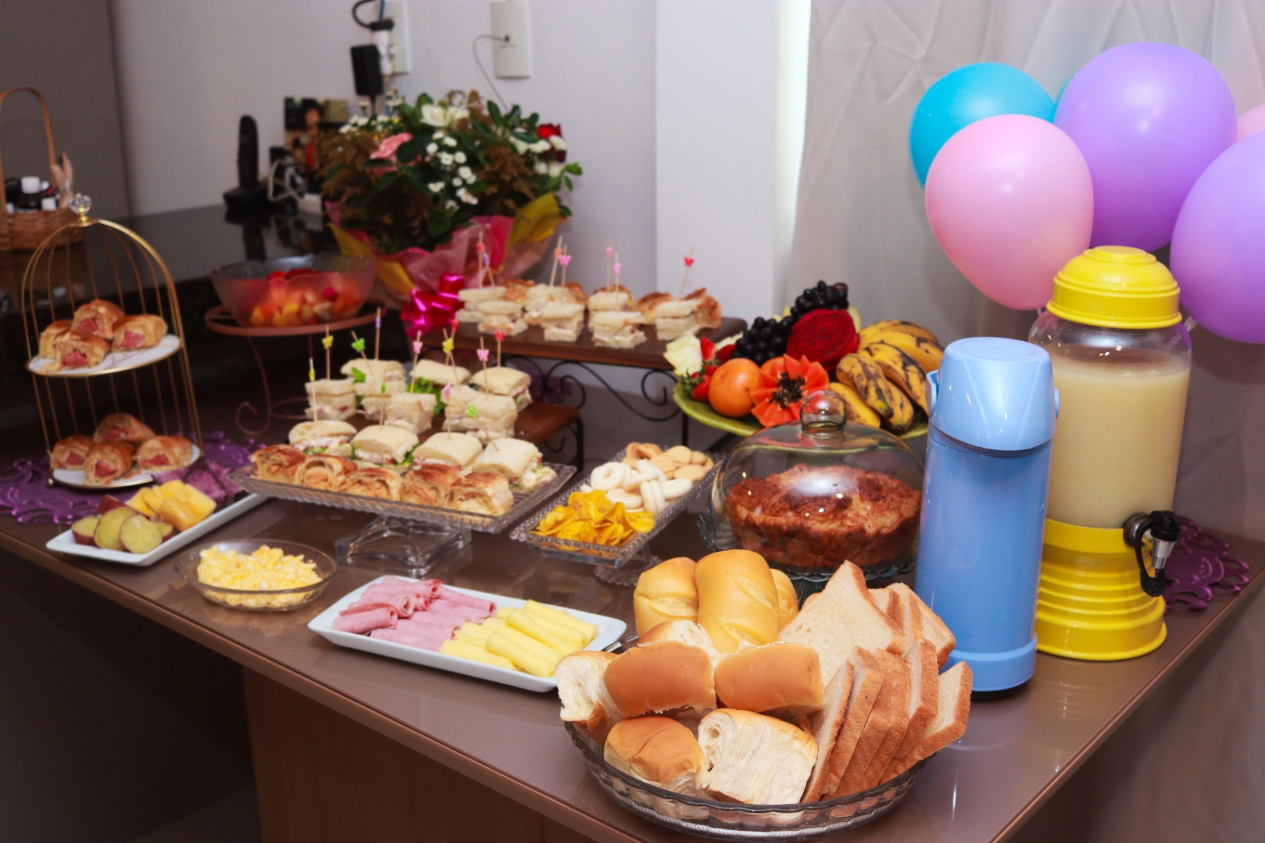 Mesa de café da manhã com sanduíches, frutas e bebidas